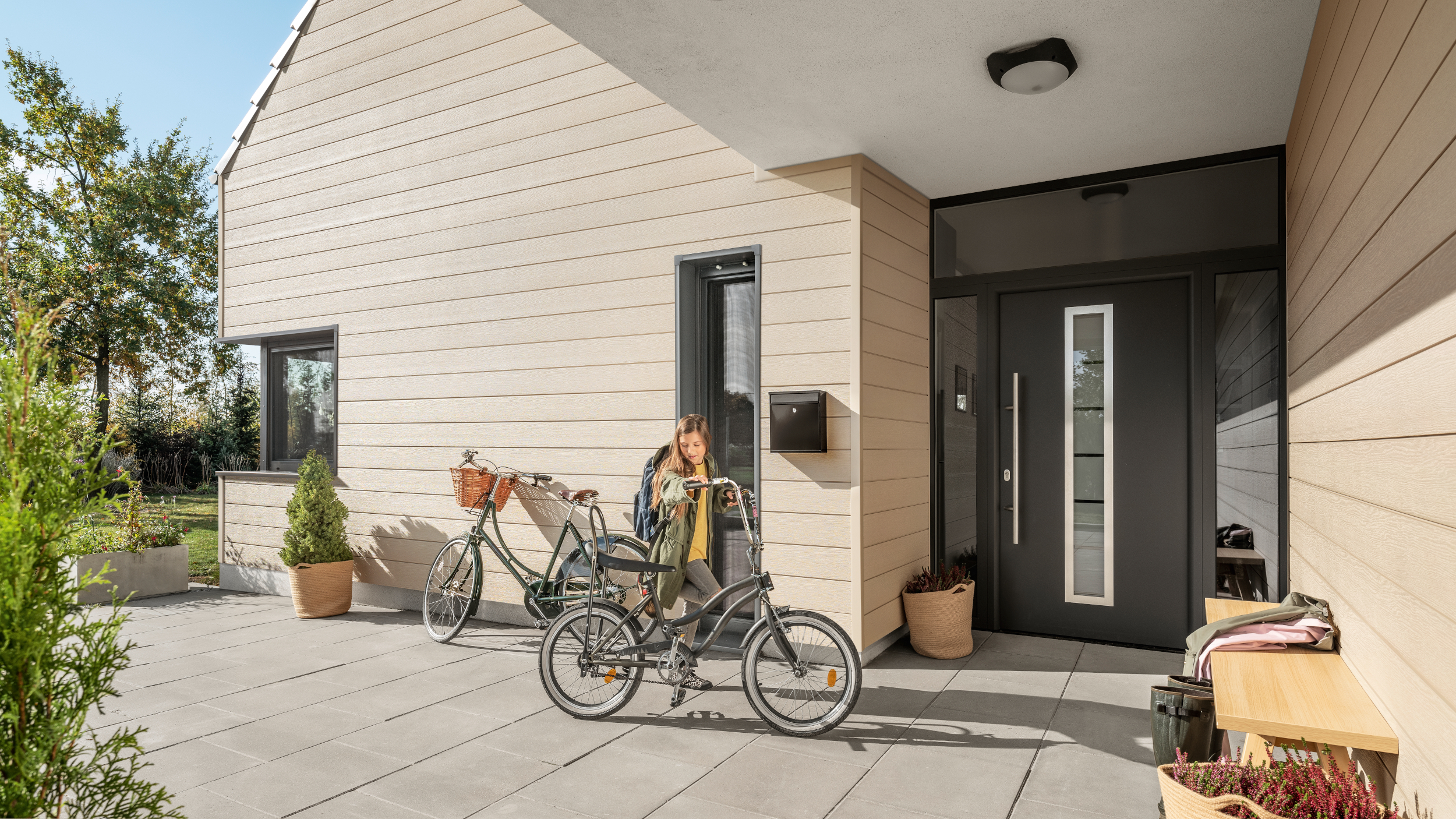Child on bicycle in front of house with PVC siding